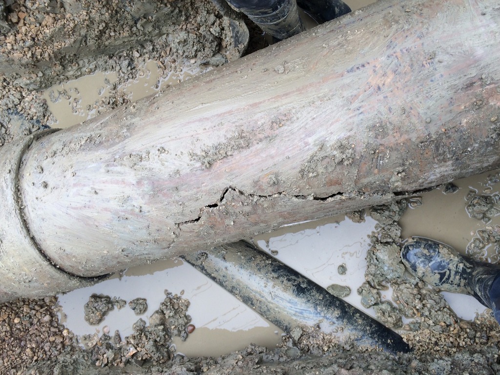 Cracked pipe in muddy excavation