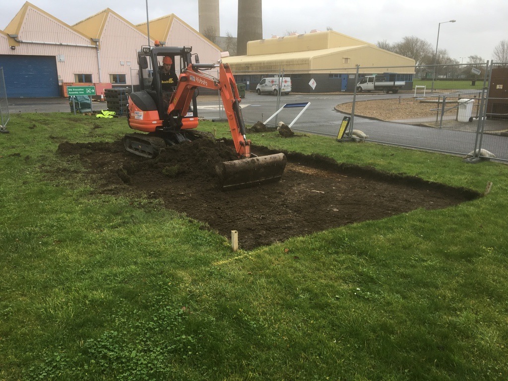 Excavator digging a grassy area