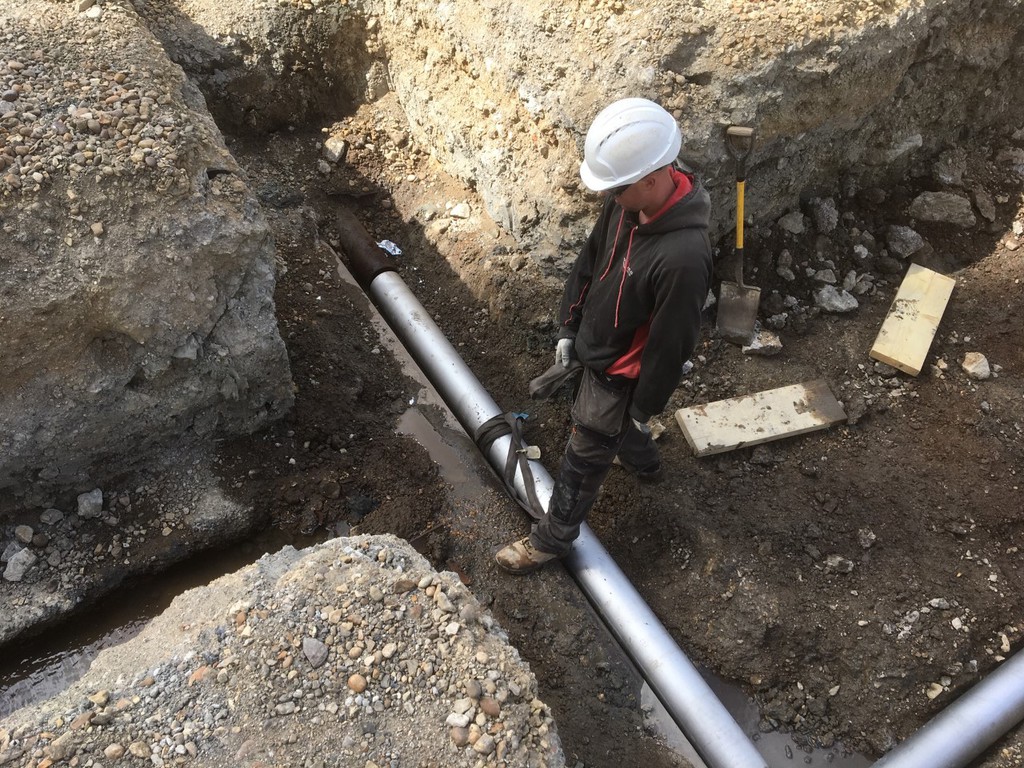 Worker in trench with pipe